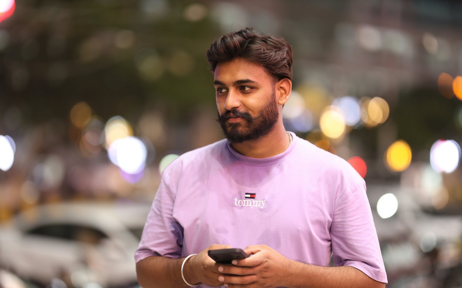 A young Indian man checking social media on his phone on a busy street